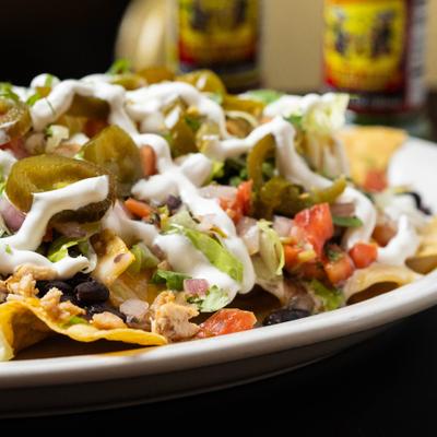 Loaded nachos topped with meat, vegetables and creamy sauce.