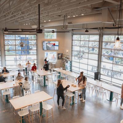 The interior of the restaurant, people, tables, chairs, windows.