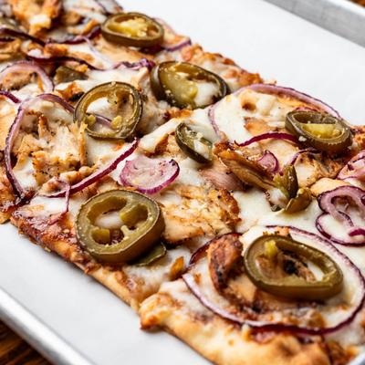 BBQ chicken flatbread topped with jalapenos and red onions.