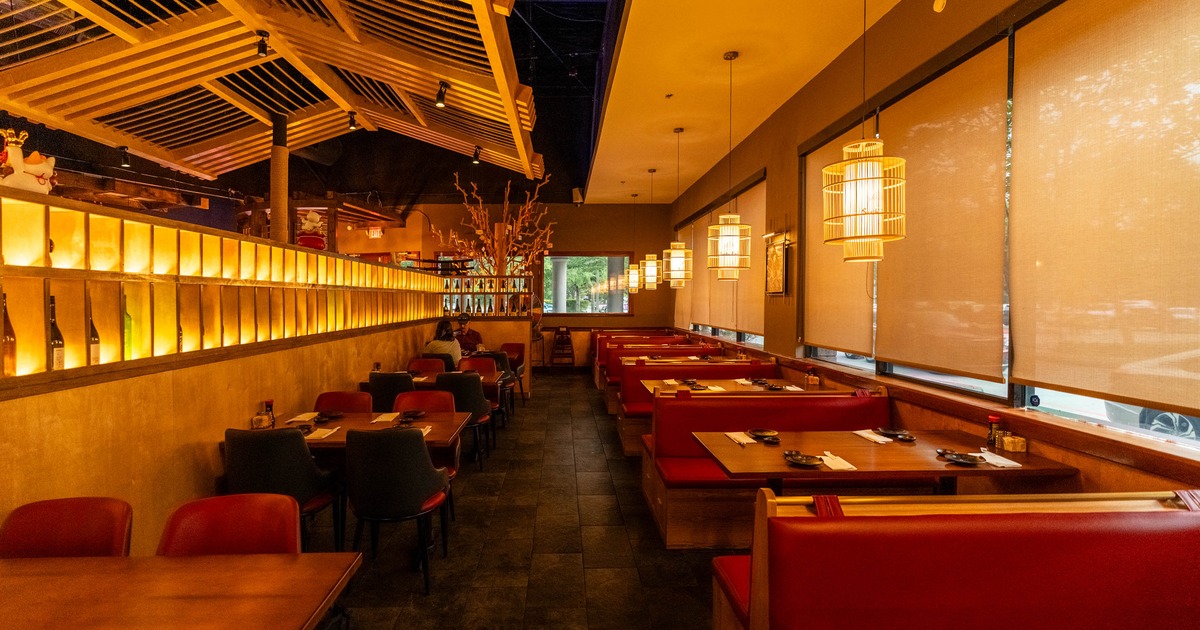 Interior featuring a mix of booths and tables, warm lighting and wood-latticed ceilings