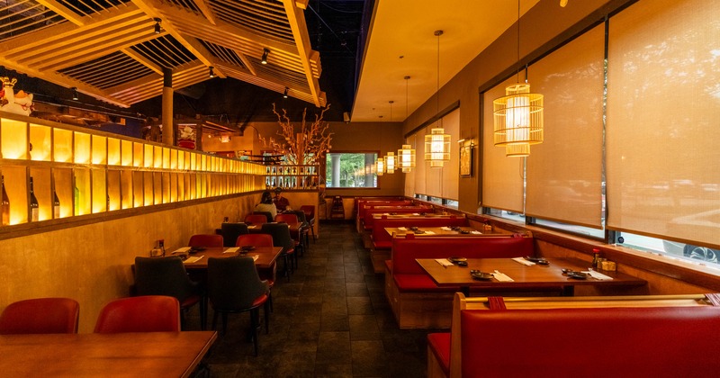 Interior featuring a mix of booths and tables, warm lighting and wood-latticed ceilings