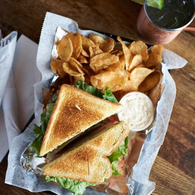 Club Sandwich served with chips and a dip on the side.