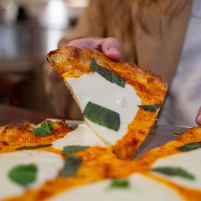 A slice of Pizza Margherita being lifted from the rest of the pizza.