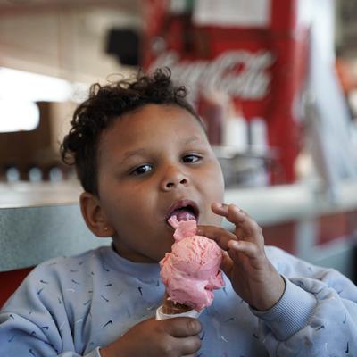 child licking strawberry ice cream cones.