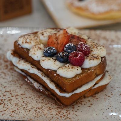 Stuffed French toast topped with whipped cream, fresh berries and a dusting of cocoa powder.
