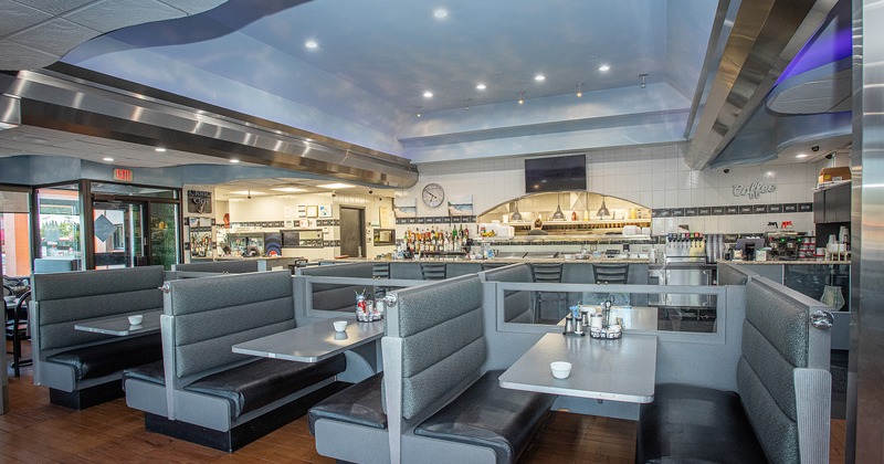 Cozy interior dining area with upholstered dining booths ready for guests and an open kitchen behind