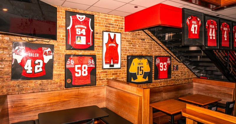 Interior, ''U'' shaped seating booths with tables, red brick wall, framed jerseys on the wall