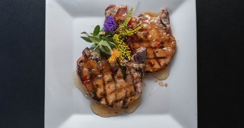 Two grilled pork chops served on a white plate