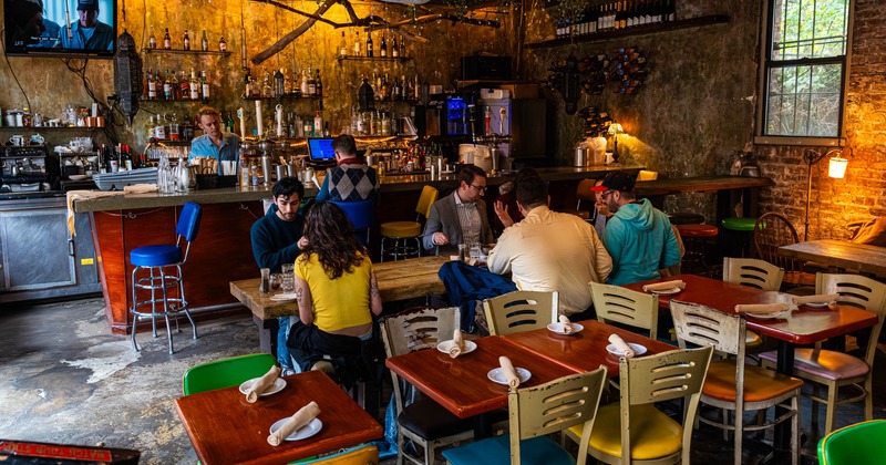 Dining area, patrons are seated at wooden tables and at bar