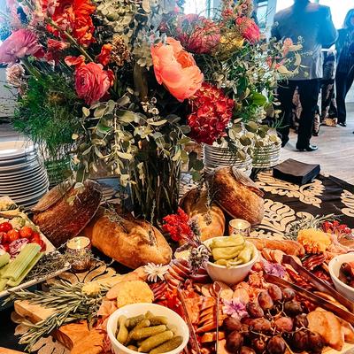 Charcuterie spread with bread, stacked plates, and a floral centerpiece.