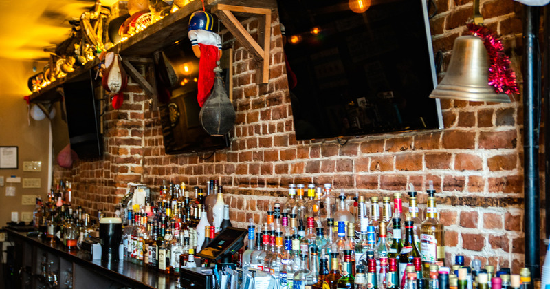 2 TVs and bottles with drinks behind the bar