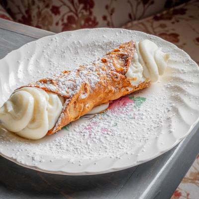 Italian cannoli filled with sweet ricotta cream and topped with powdered sugar.