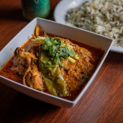 Goat curry bowl, with a side of rice.