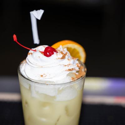 Pain reliever cocktail topped with whipped cream, orange slice and a cherry.