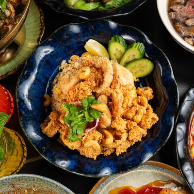 Trio seafood pineapple fried rice dish, surrounded by various other food dishes.