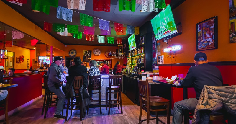 Bar area, guests, tv screens, tables, chairs