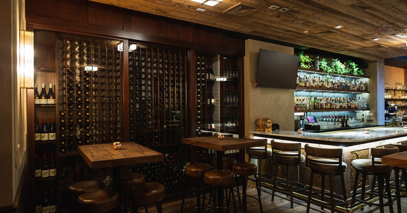 Interior, tables, chairs, counter, stacked bottles, wall TV