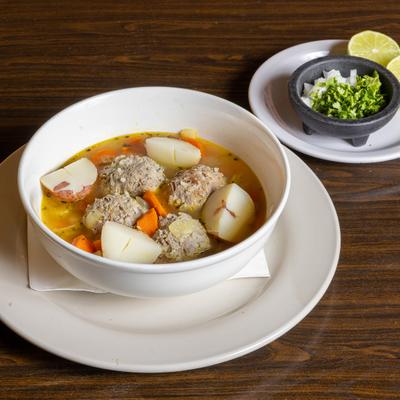 Meatball soup, with onion, cilantro, and lime on the side.