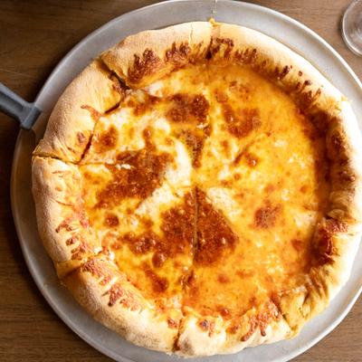 Deep Dish Pizza topped with melted cheese and served on a metal tray.