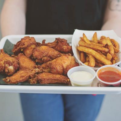 An employee handing out the wings and fries platter, front view, closeup.