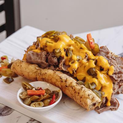 A served Italian beef sandwich with peppers on the side.