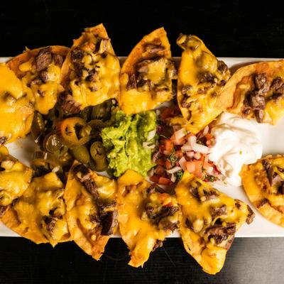 Lunch Nachos topped with meat and cheese, served with guacamole and sour creme.