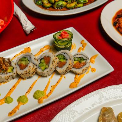 Sushi platter features salmon and avocado rolls drizzled with spicy mayo.