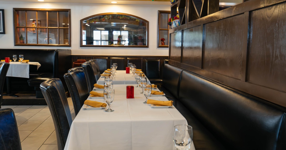 Restaurant interior with tables set with wine glasses, black leather seating