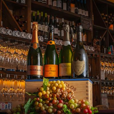 Sparkling wine bottles displayed above green grapes.