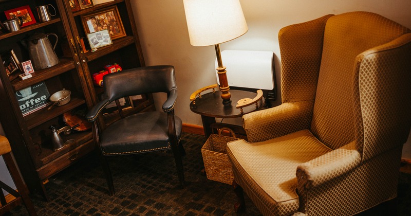 An armchair and a leather chair next to a small table with a lamp