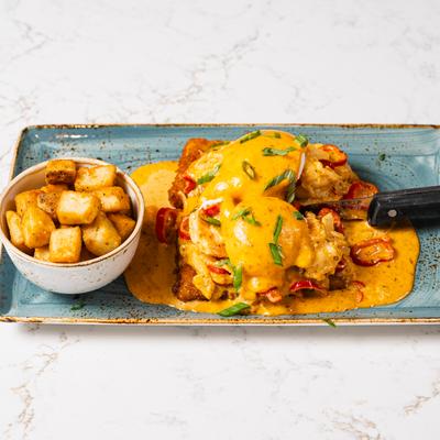 An egg Benedict dish served with breakfast potatoes.