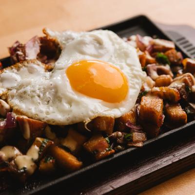 Sizzling sisig topped with a fried egg, close up.