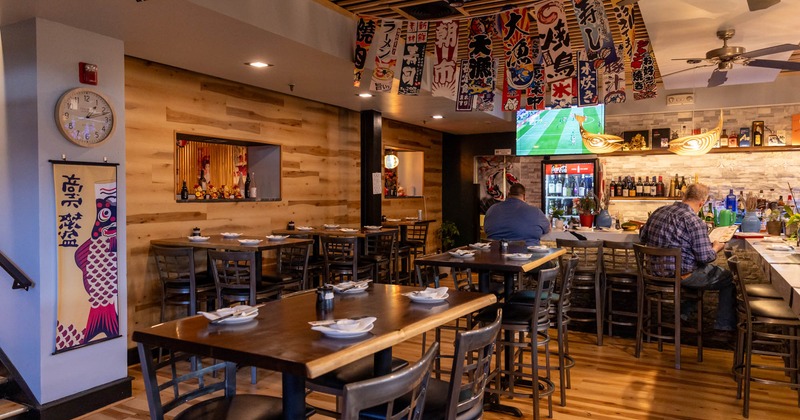 Interior, high seating tables with stools, ready for guests, bar with stools in the back