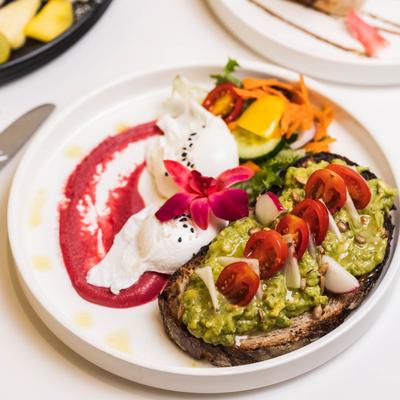 Avocado toast with grape tomatoes, sunflower seeds, radish, chili flakes, and beet hummus.