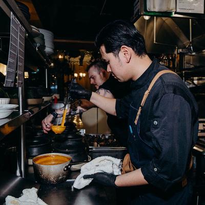 Two chefs cooking sauces.