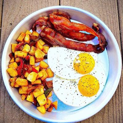 Breakfast plate with fried eggs, bacon and potatoes.