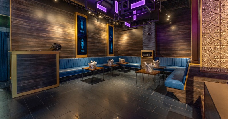 Lounge area with blue leather wall benches and coffee tables on blue tile flooring,