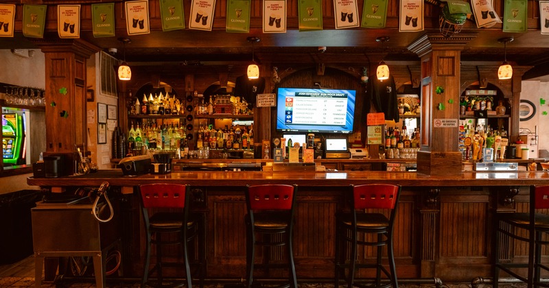 A bar decorated for St. Patrick's Day - a wooden counter, high chairs and Guinness banners