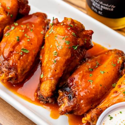 Chicken wings with mango sauce and herb garnish.