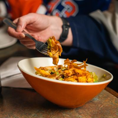 Person holding a fork with a bite of food over  Mexi Bowl.