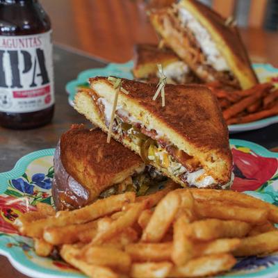 Grilled cheese sandwich with jalapenos and bacon, served with fries and a beer.
