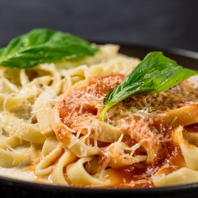 Fettuccine pasta with tomato sauce, cheese, and basil.