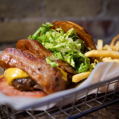 Bacon cheeseburger with lettuce served with fries.