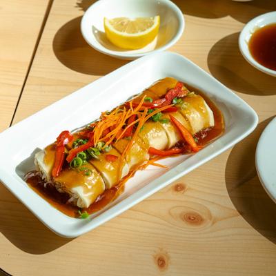 A plate with fresh Thai spring rolls, served on a table with various other dishes.