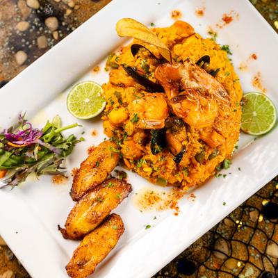 Seafood Paella served with salad and fried plantains on the side.