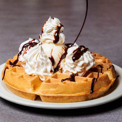 Waffle topped with ice cream, whipped cream and chocolate sauce.