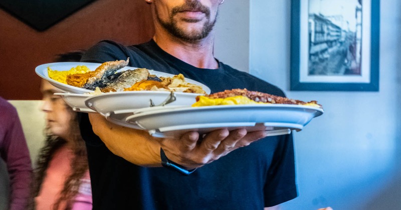 Restaurant employee holding five plates with served food on one hand