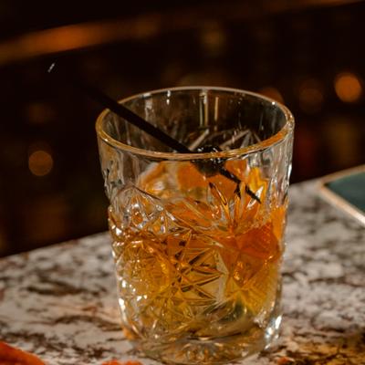 Old Fashioned cocktail garnished with a cherry on a pick.