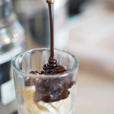 adding hot fudge to a coed sundae.