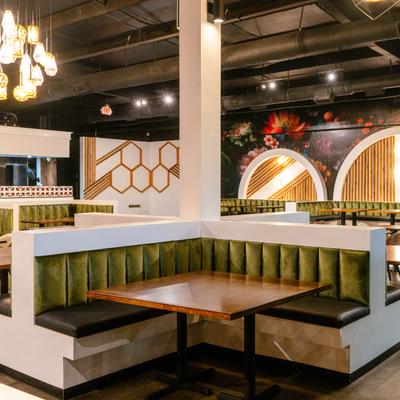 Interior featuring distinctive velvet green booths and warm lighting.